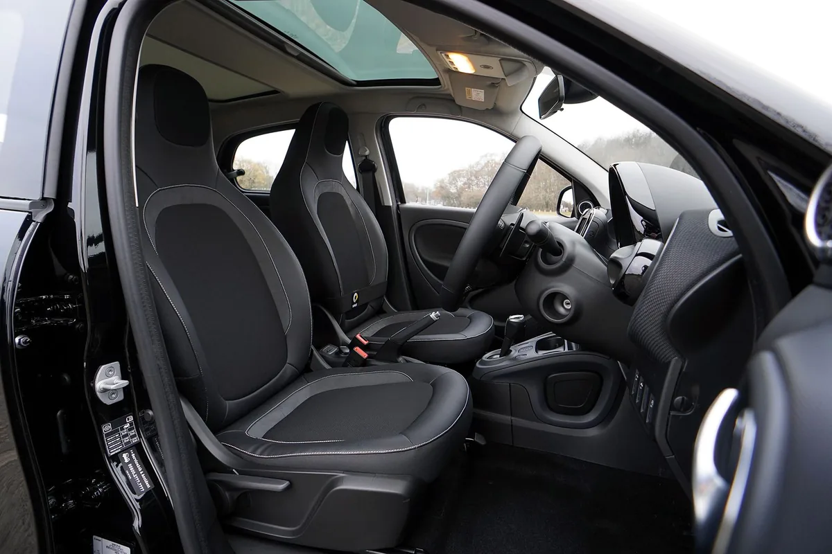 Interior of a black car with the driver door open and empty seats